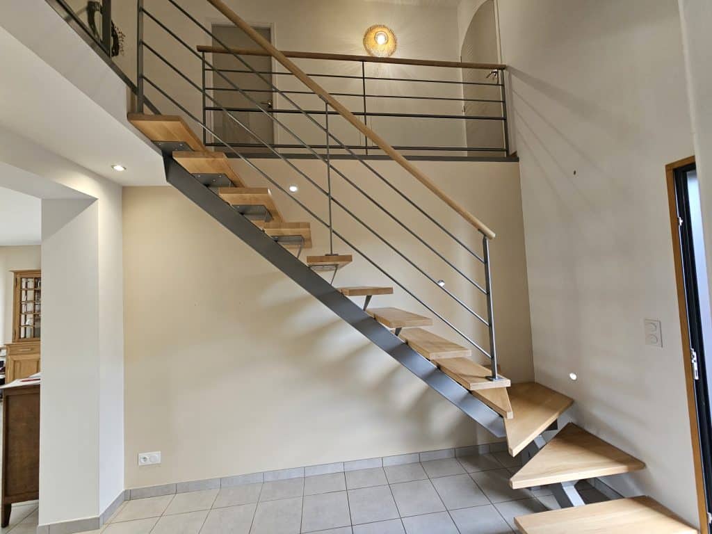 Escalier suspendu métal et bois sur mur beige – Caen