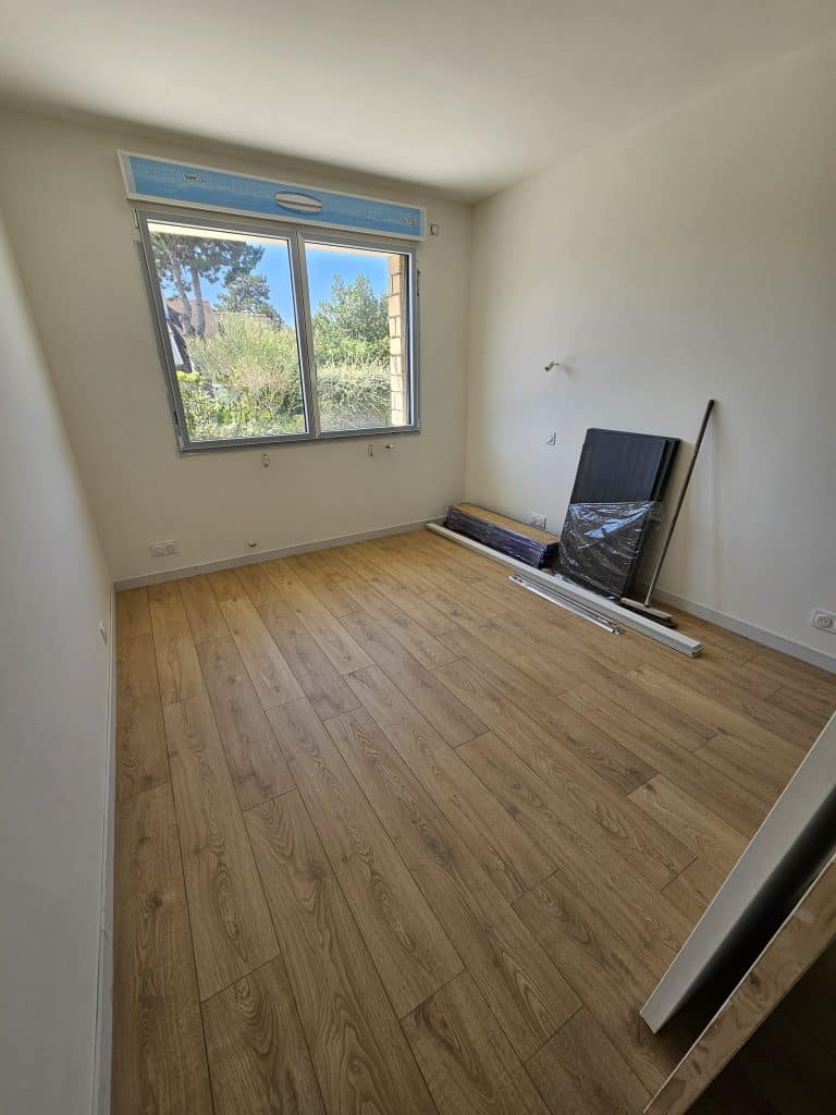 Chambre vide avec sol bois clair et baie vitrée – Caen